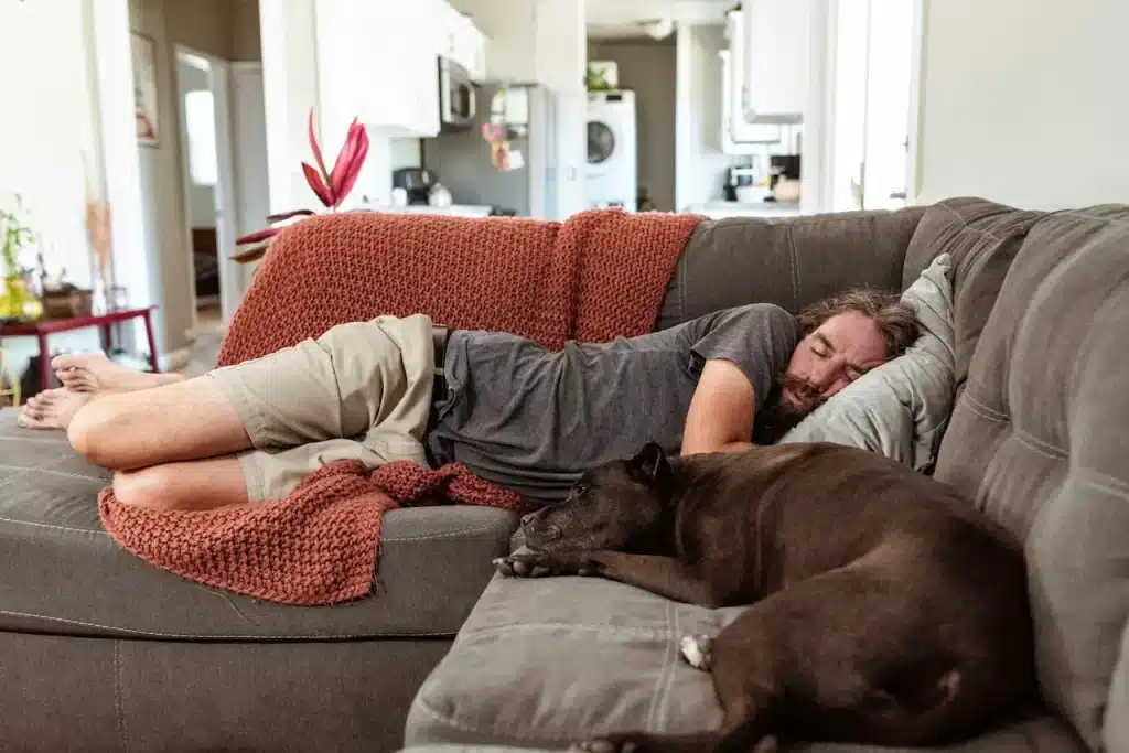 A Man Sleeping on a Couch Next to a Dog