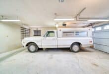 A white truck parked in a garage next to a garage door