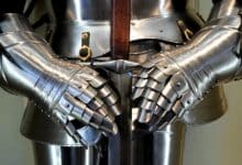 Detailed view of medieval armor gauntlets holding a sword.