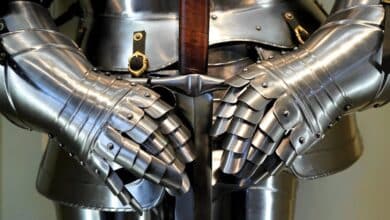 Detailed view of medieval armor gauntlets holding a sword.