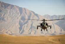 black helicopter flying over brown field during daytime