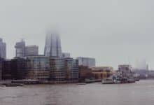 Foggy city skyline with modern buildings and river.