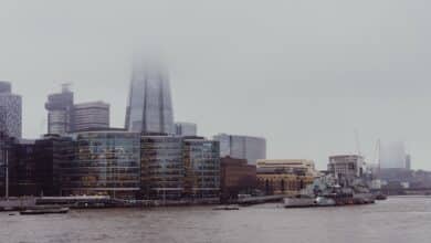 Foggy city skyline with modern buildings and river.