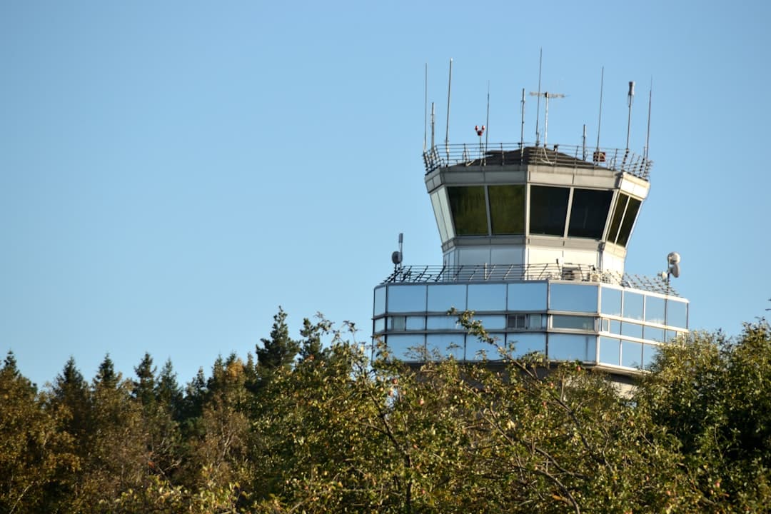 An airport control tower stands tall above trees.