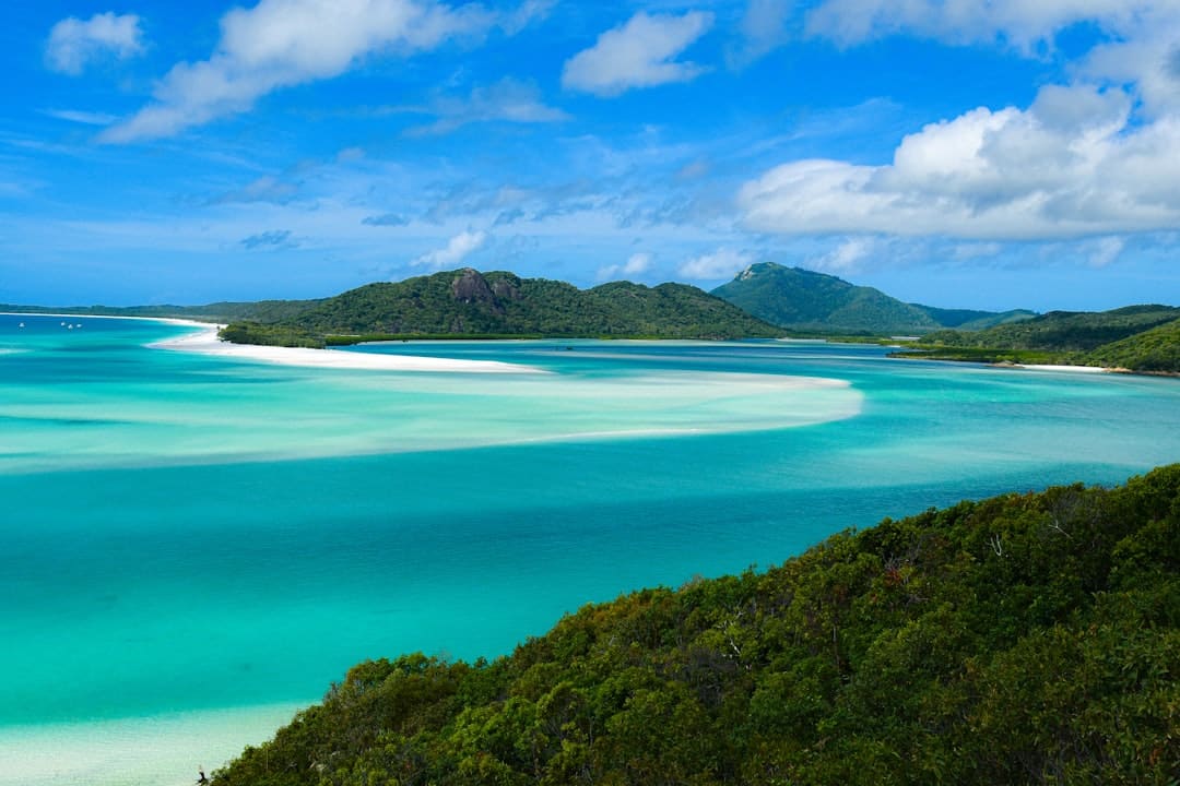 Turquoise water and white sandbars with green hills